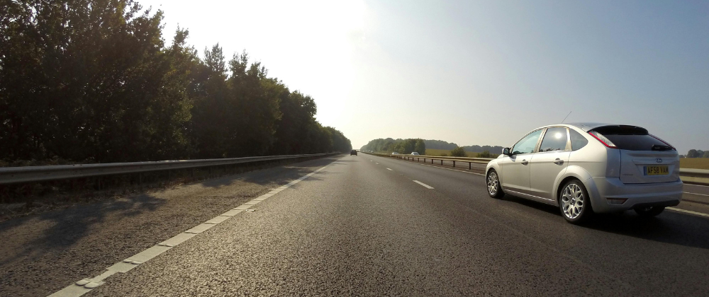 A silver Ford Focus hatchback speeding down a road.