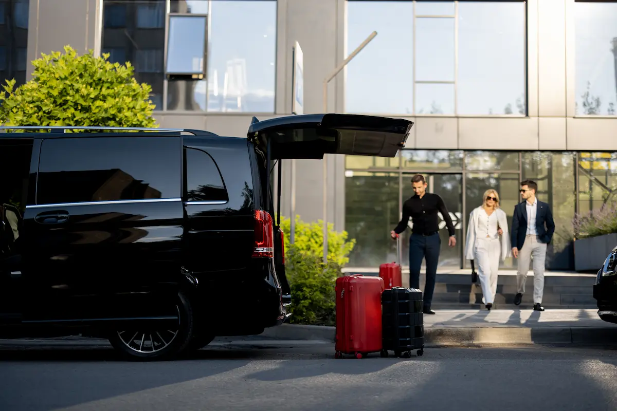 Luxury limousine Singapore rental service picking up business travelers with luggage outside a modern hotel entrance.